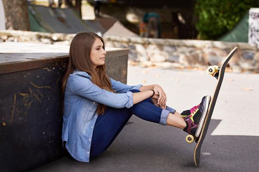 Taking a skating break. young woman sitting with her skateboard in the city.