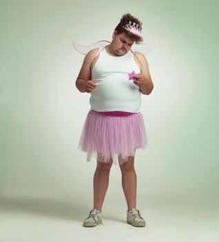 Showing his lighter side. An overweight man comically dressed-up in a pink fairy costume.