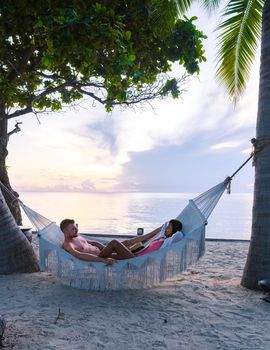 Couple men and women watching sunrise in a hammock on a tropical beach in Hua Hin Thailand