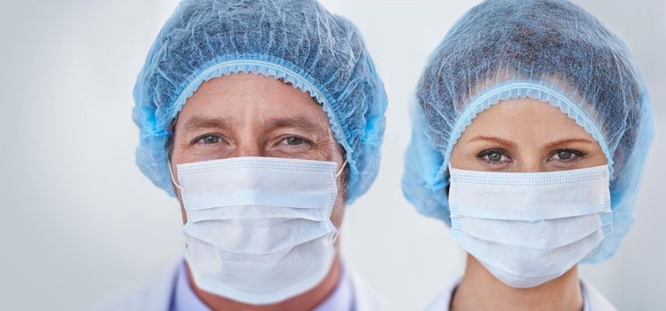 Keeping the day germ free. Head shot of two doctors wearing a protective mask and a hairnet while standing indoors.