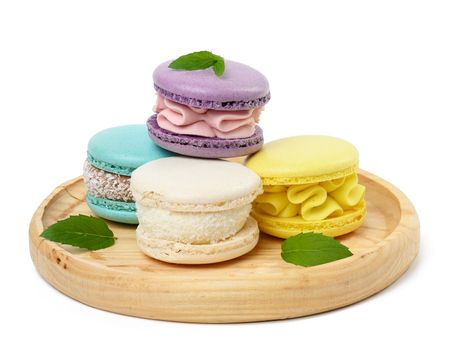 Multi -colored baked macaroons on a wooden plate
