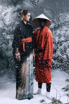 Fashion fantasy. Fashion shot of a man and woman wearing oriental-style clothing in a snowy forest