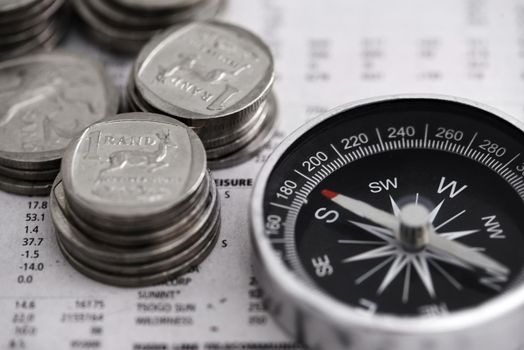 Finding my way into the market. Studio shot of coins and a compass on the business section of a newspaper.