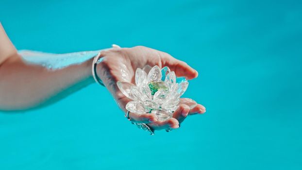 Woman holding fragile lotus flower. Clean water drops are dripping from crystal. Concept of religion, kundalini, meditation, chakras, spiritual inner world