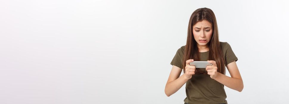 Happy attractive brunette girl joying win in video game on smartphone, isolated over grey background