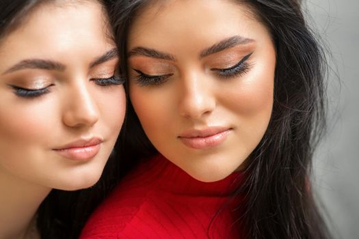 Portrait of young beautiful two women with long lashes and closed eyes after eyelash extensions.