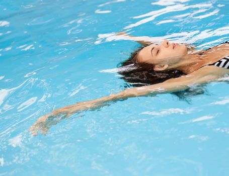 Carefree and relaxed. A cropped shot of a beautiful young woman floating in a clear pool.