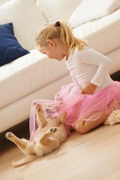 Lets play ballerina together. a little girl in a tutu playing with a puppy