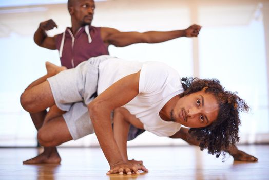 Keeping fit with capoeira. two young men practicing in a dance studio.