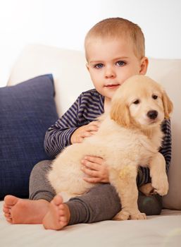 Snuggling his way into his heart. An adorable little boy with his puppy at home.