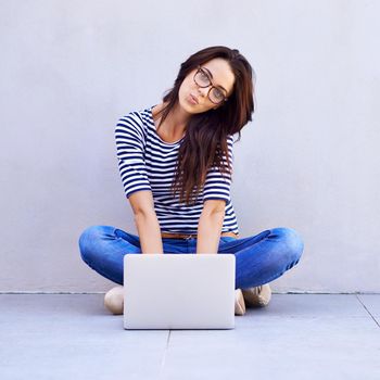 My digital life. an attractive young woman making a face while sitting on the floor with her laptop.
