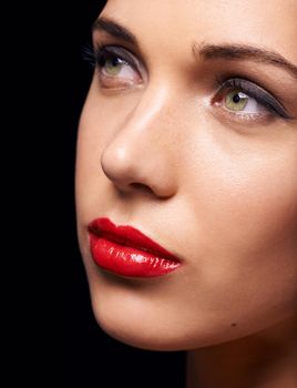 Lady in red. A closeup of a beautiful young woman wearing red lipstick, isolated on black.