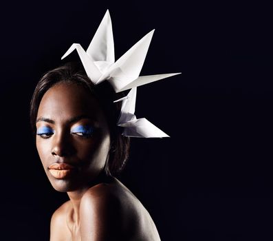 Haunting beauty of the african queen. a beautiful ethnic woman posing with origami birds on her head.