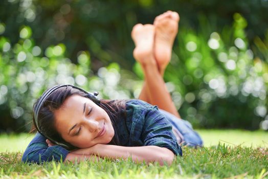 Sweet dreams on the grass. an attractive young woman lying on the grass and listening to music.