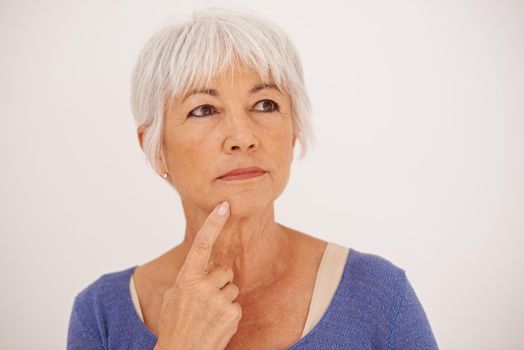 Wonder what I should do for dinner. Cropped image of a mature woman deep in thought with her finger on her chin.