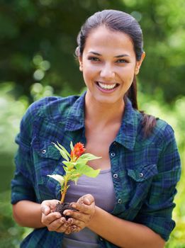 Having fun in the garden. Portrait of an attractive young woman holding a young plant