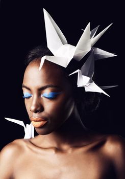 She epitomizes African beauty. a beautiful ethnic woman posing with origami birds on her head and shoulders.
