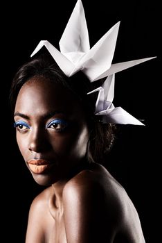 Sultry silent of the african beauty. a beautiful ethnic woman posing with origami birds on her head.