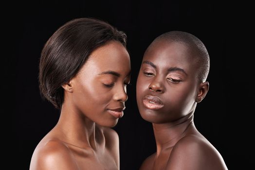 True African beauty. Two beautiful african women standing together against a black background.