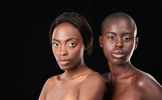 Naturally beautiful. Two beautiful african women posing in front of a black background with bare shoulders.