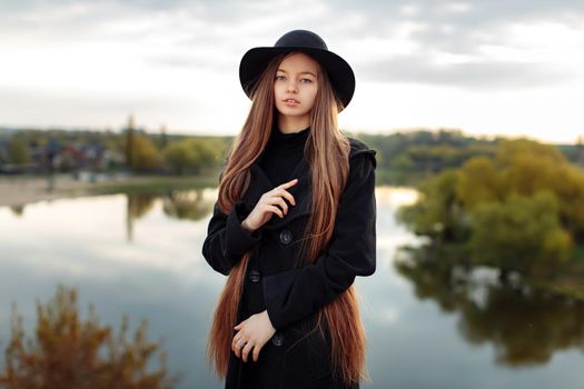 Young beautiful fashionable woman in black hat, with long hair. Female fashion, beauty concept. Outdoor.