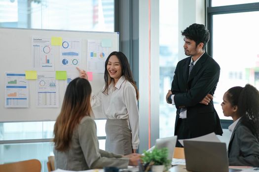 Female Operations Manager Holds Meeting Presentation for a Team of Economists. Asian Woman Uses Digital Whiteboard with Growth Analysis, Charts, Statistics and Data. People Work in Business Office.
