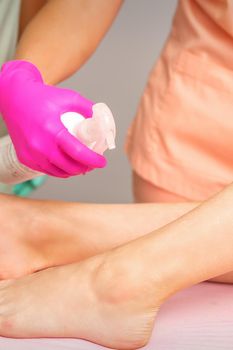 A beautician sprays a disinfectant on the feet of a young woman before the epilation procedure. Foot depilation.