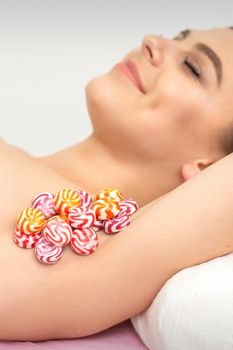 Colored round candies under the female armpit, close up, depilation armpit concept.