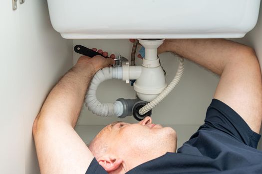 do-it-yourself plumbing repair by a man under the sink