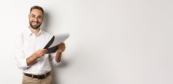 Employer looking satisfied at CV, reading document and smiling, standing over white background