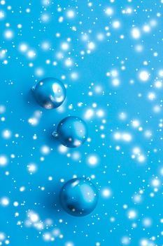 Christmas baubles on blue background with snow glitter, luxury winter holiday card