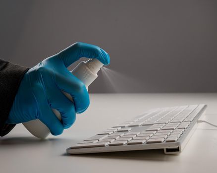 Close-up of a woman disinfects a white computer keyboard. Slow motion.