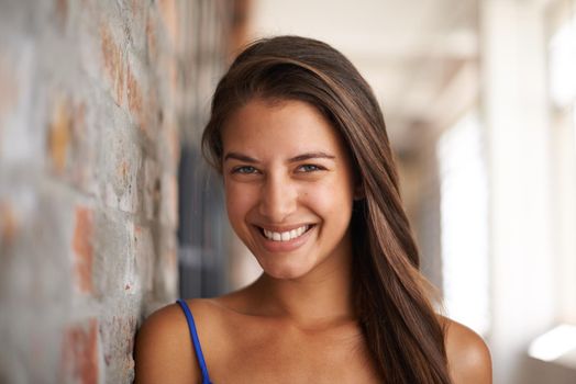 Youthful happiness. Cropped portrait of an attractive young woman leaning against awall.