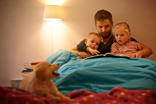 Bonding before bedtime. A father reading a bedtime story to his kids.