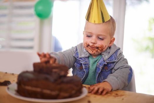 That cake never stood a chance. a young boy eating his birthday cake before the party.