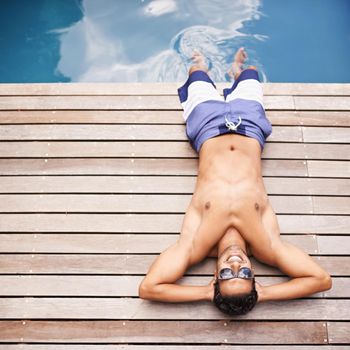 Taking it easy poolside. High angle shot of a young man lying by a pool.