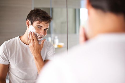 Protecting his face with the correct shaving foam. a young man looking in a mirror to apply shaving foam.