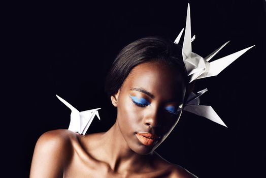 The beauty of Africa. a beautiful ethnic woman posing with origami birds on her head and shoulders.