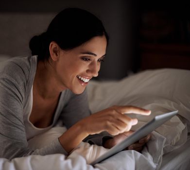 Online retail therapy in comfort. an attractive young woman using her tablet in bed.