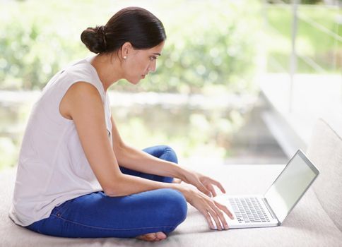My wifi lets me browse anywhere I want. an attractive young woman using a laptop while relaxing at home.