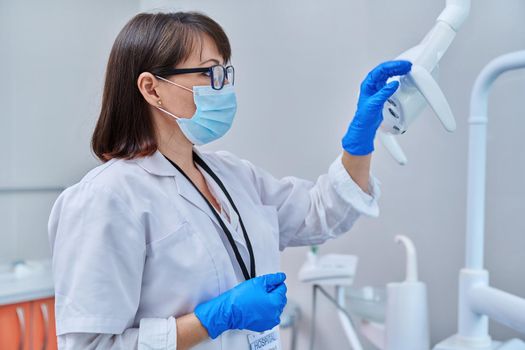 Serious confident female doctor dentist in face mask in dental office, profile view. Dentistry, medicine, specialist, career, dental health care concept