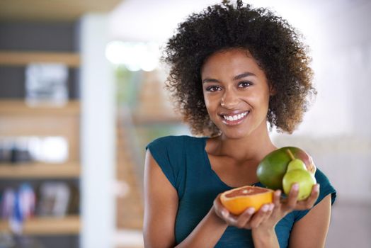 The key to a healthy smile. Portrait of an attractive young woman holding a bunch of different fruit.