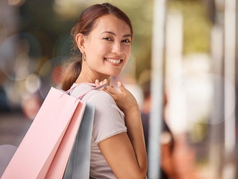 Shopping, fashion and portrait of woman with shopping bags, smile and happy after buying luxury designer clothes. Retail, discount and asian girl or customer travel in street to purchase sales items