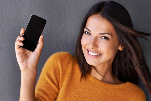 This makes staying connected easier. Closeup portrait of an attractive young woman holding up a mobile phone.