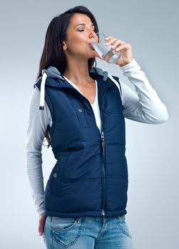 Quenching her thirst. A studio shot of a beautiful woman drinking a glass of water.