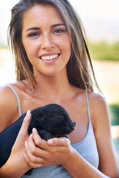 Getting to know the newest member on the farm. A young woman holding a cute piglet.
