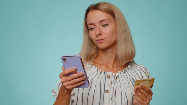 Young woman using credit bank card and smartphone while transferring money purchases online shopping