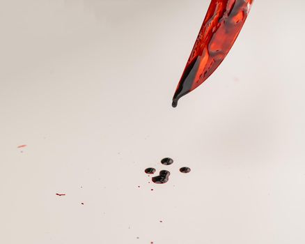 Close-up of a sharp knife covered in blood on a white background.