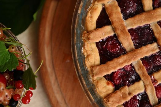Cropped view classic American festive cherry pie with crispy sweet pastry lattice and fresh ripe organic berries in bowl