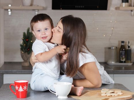 Mom kisses the child in the kitchen. A series of photos from everyday life in a real interior